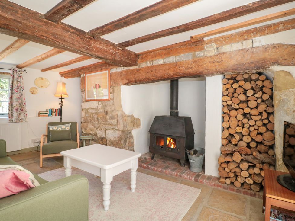 A living room with a wood stove and seating at Old Farm Cottage in Warminster