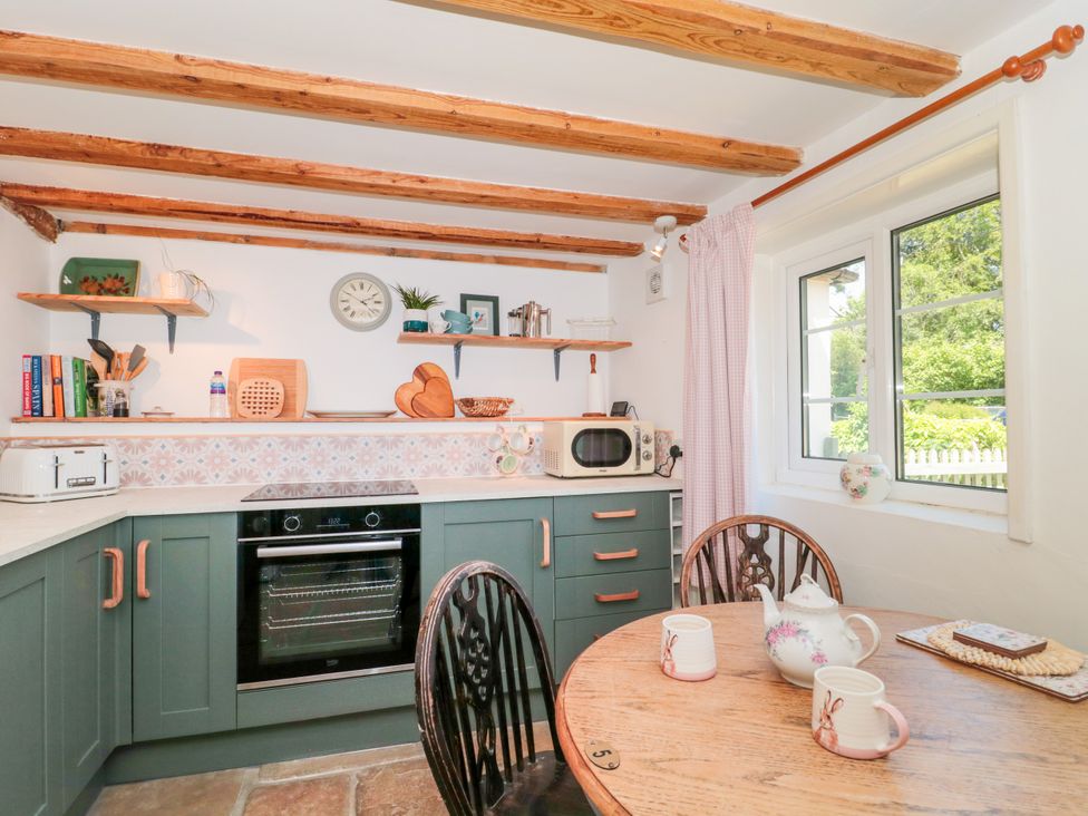 A kitchen with a stove, microwave, and table at Old Farm Cottage in Warminster
