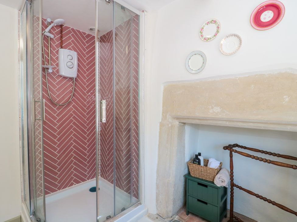 A shower with glass doors and decorative items at Old Farm Cottage in Warminster