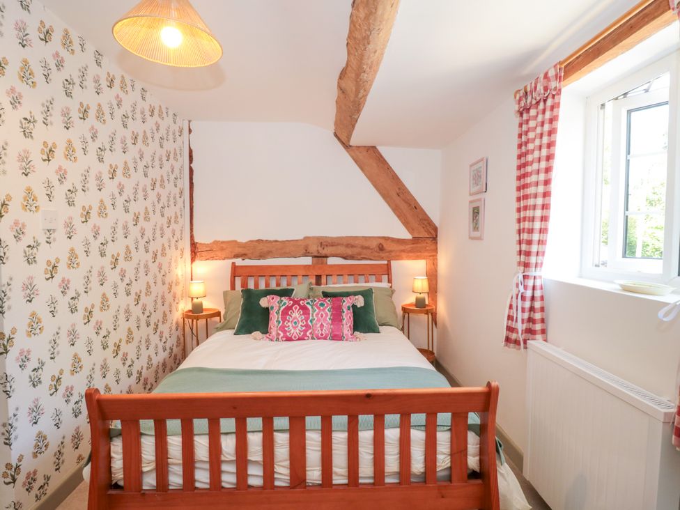 A bedroom with a bed and floral wallpaper at Old Farm Cottage in Warminster