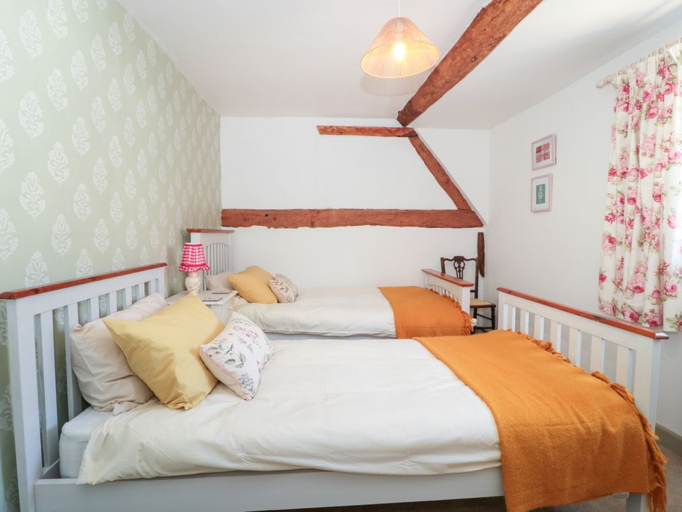 A bedroom with two beds and a chair at Old Farm Cottage in Warminster