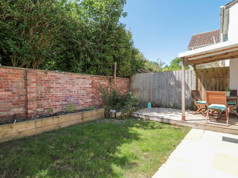 A garden with a brick wall and wooden decking at Old Farm Cottage in Warminster