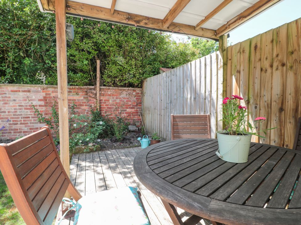 A garden with a round wooden table and chairs at Old Farm Cottage in Warminster