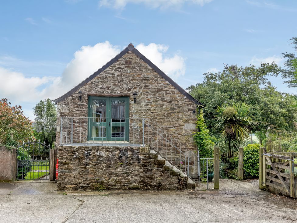 A stone building with a green door at the top of stairs surrounded by plants at The Loft in Bodrean near Truro