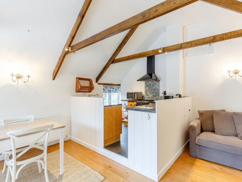 A kitchen area with wooden beams a dining table with chairs and a sofa at The Loft in Bodrean near Truro