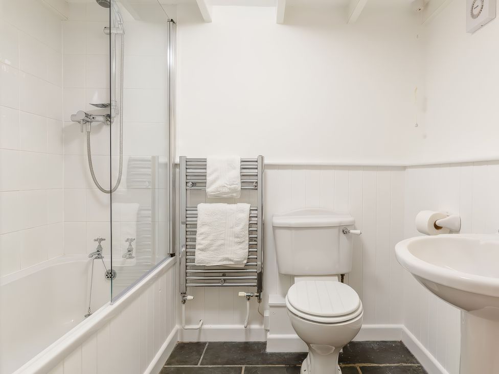 A bathroom with a bathtub shower combination a towel rack with white towels a toilet and a sink at The Loft in Bodrean near Truro