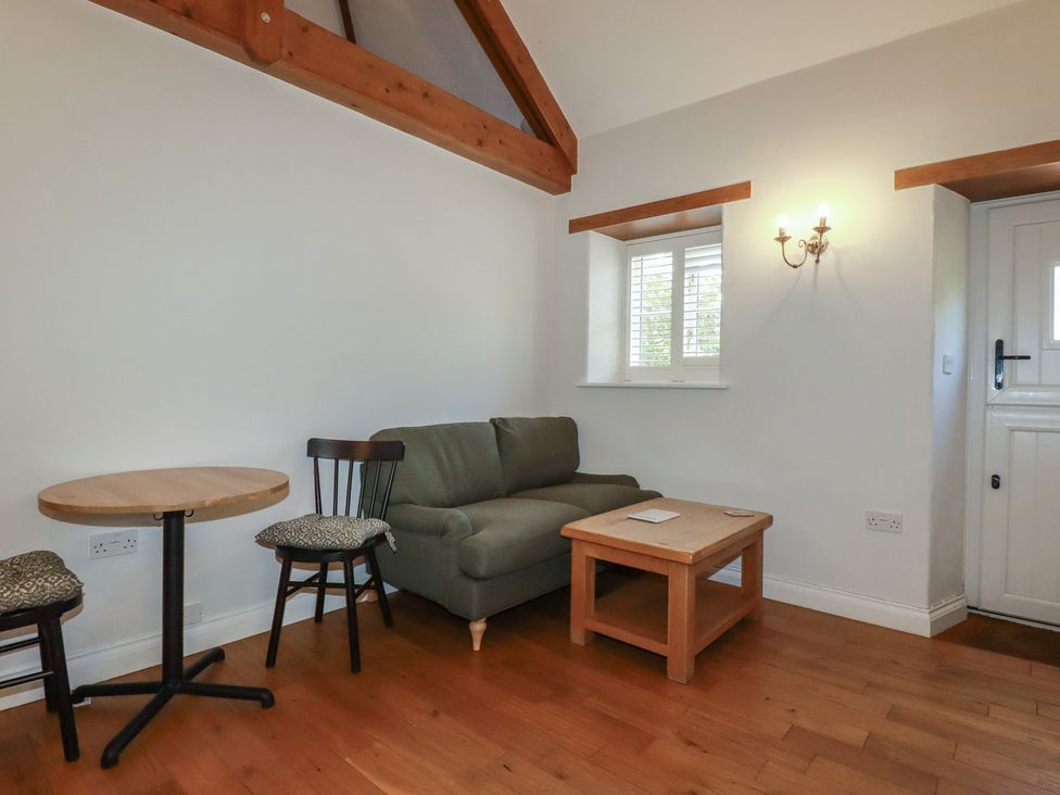 A living room with a green sofa a wooden coffee table two chairs and a small round table at The Copper House in Bodrean near Truro