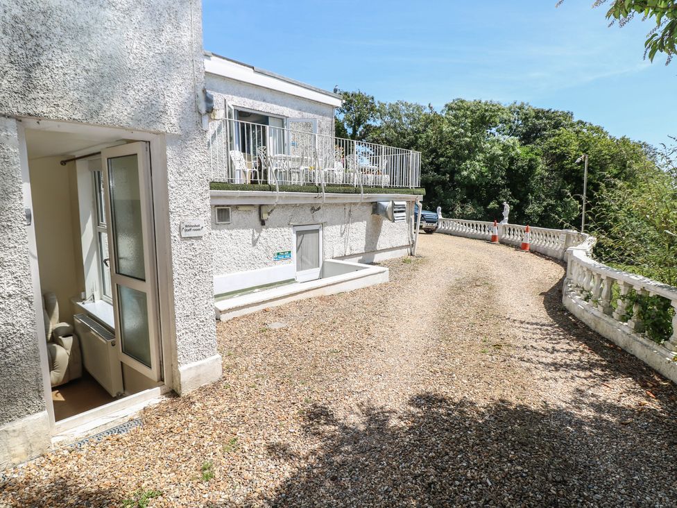An outdoor view of a house with a balcony and gravel driveway at Whiteshell in Langland near Mumbles