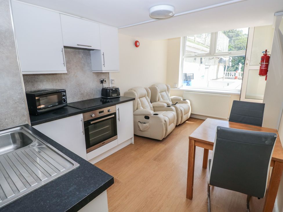 A kitchen area with appliances and seating at Whiteshell in Langland near Mumbles