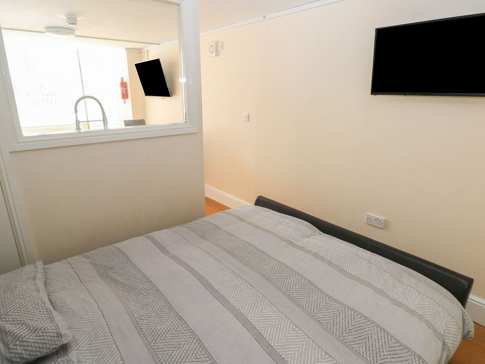 A bedroom with a bed and television at Whiteshell in Langland near Mumbles
