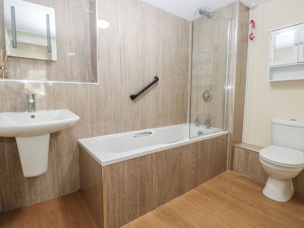 A bathroom with a sink, toilet, and bath tub at Whiteshell in Langland near Mumbles