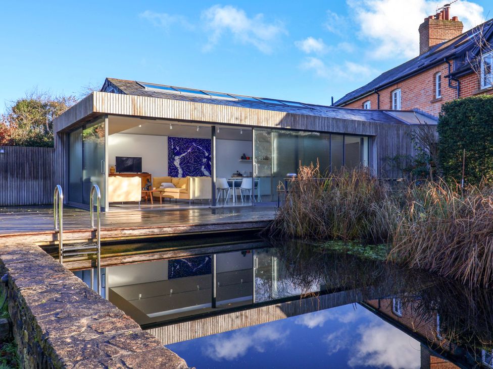 A modern house with glass doors and a pool at 2 Bredy Cottages Burton Bradstock
