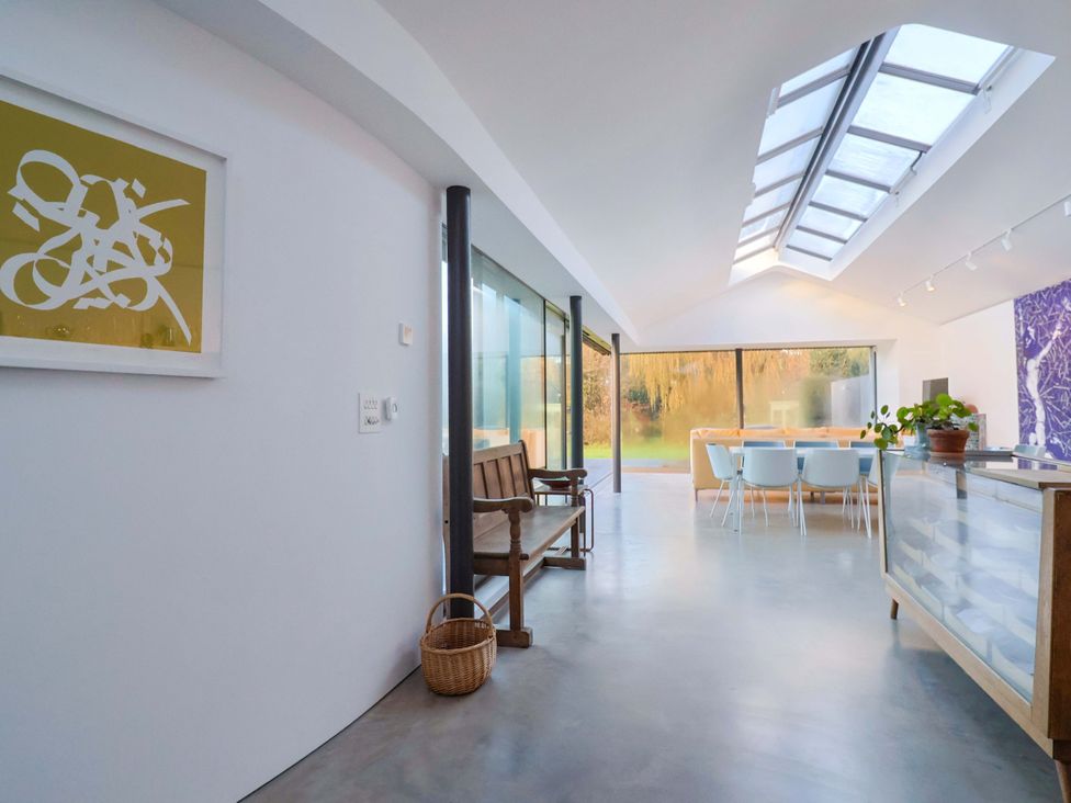 A kitchen with a glass wall and dining area at 2 Bredy Cottages Burton Bradstock