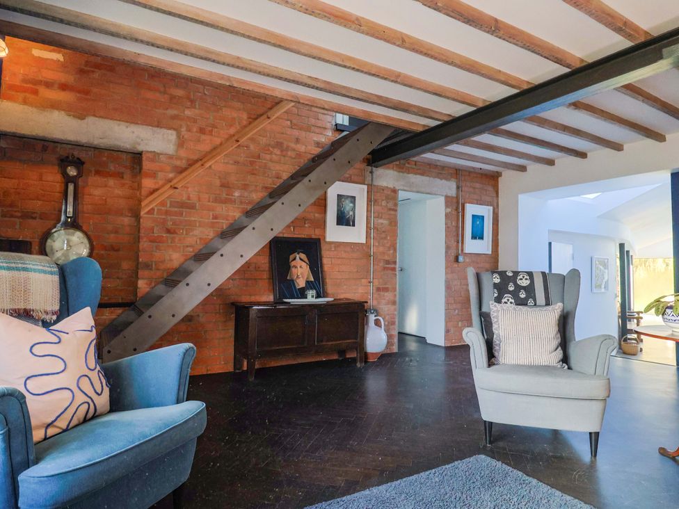 A living room with an armchair and staircase at 2 Bredy Cottages in Burton Bradstock