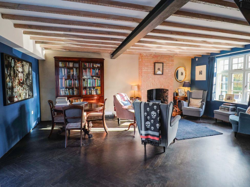 A living room with a bookshelf and seating area at 2 Bredy Cottages in Burton Bradstock