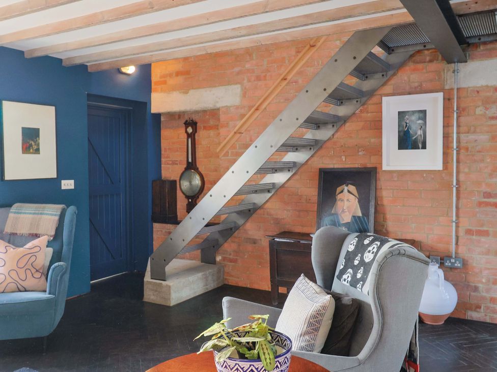 A living room with a staircase and sofa at 2 Bredy Cottages in Burton Bradstock