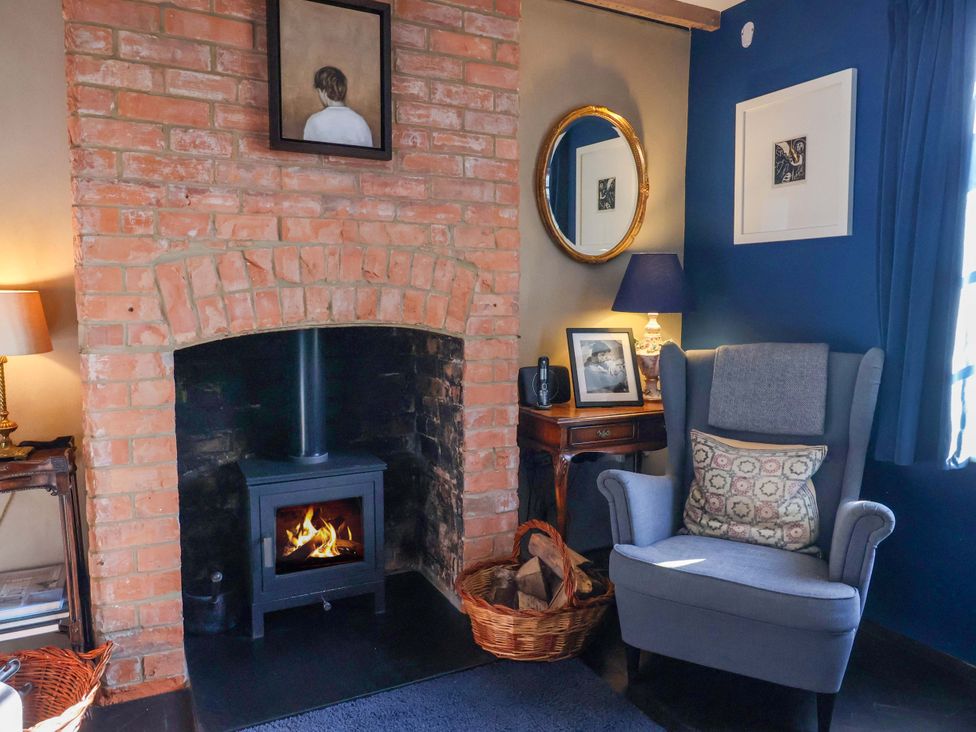 A snug with a fireplace and armchair at 2 Bredy Cottages Burton Bradstock