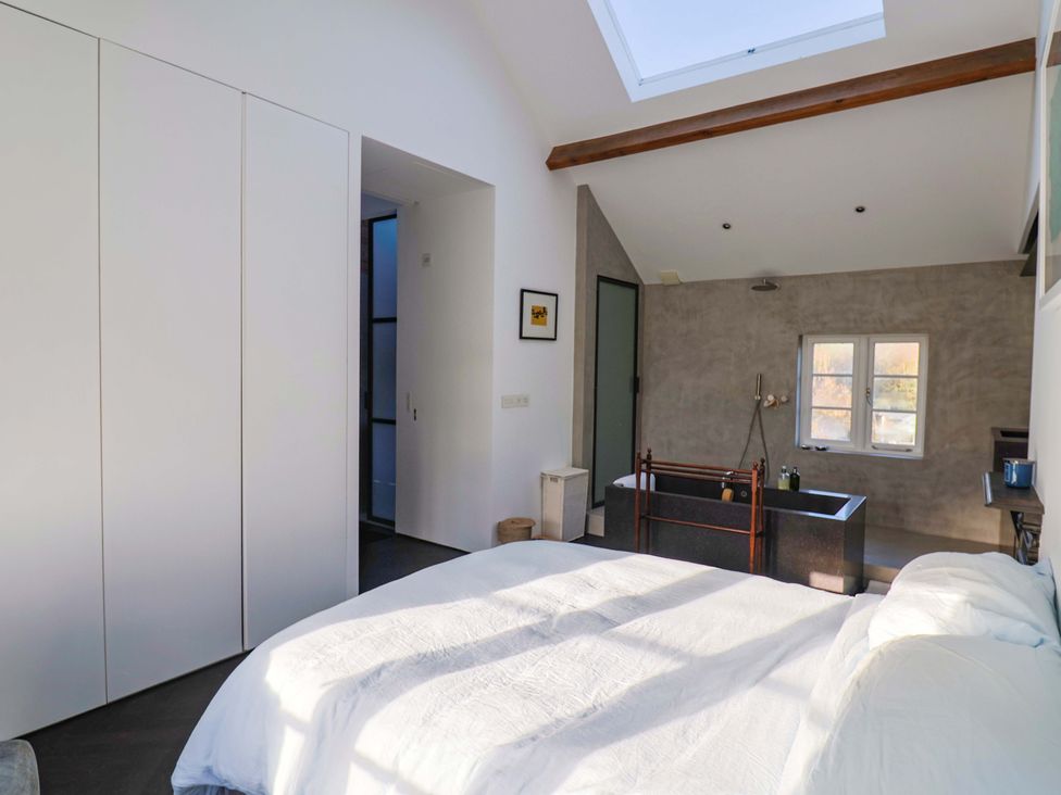 A bedroom with a bed and bathtub at 2 Bredy Cottages in Burton Bradstock