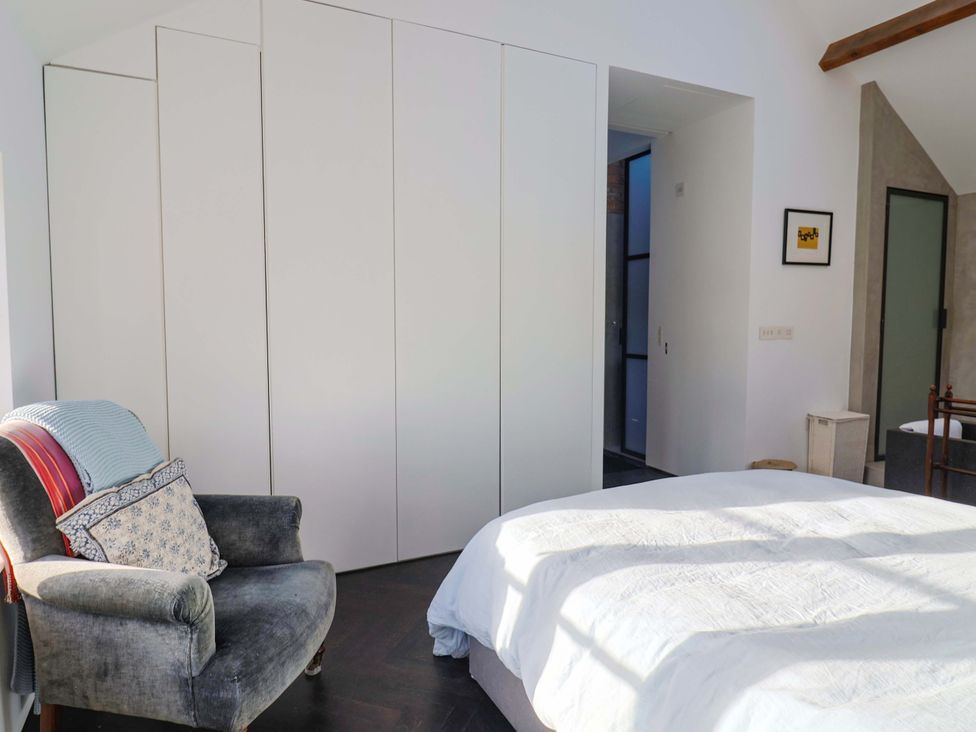 A bedroom with a bed and wardrobe at 2 Bredy Cottages in Burton Bradstock