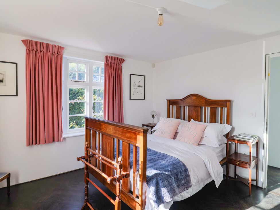 A bedroom with a bed, curtains, and a nightstand at 2 Bredy Cottages Burton Bradstock