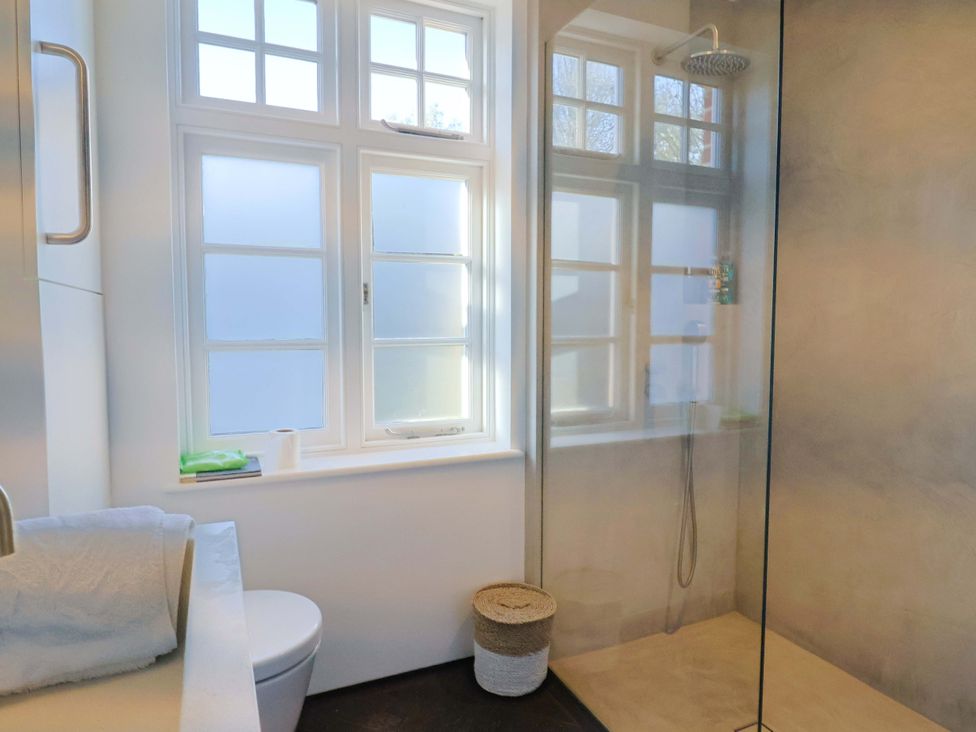 A bathroom with a shower and window at 2 Bredy Cottages Burton Bradstock