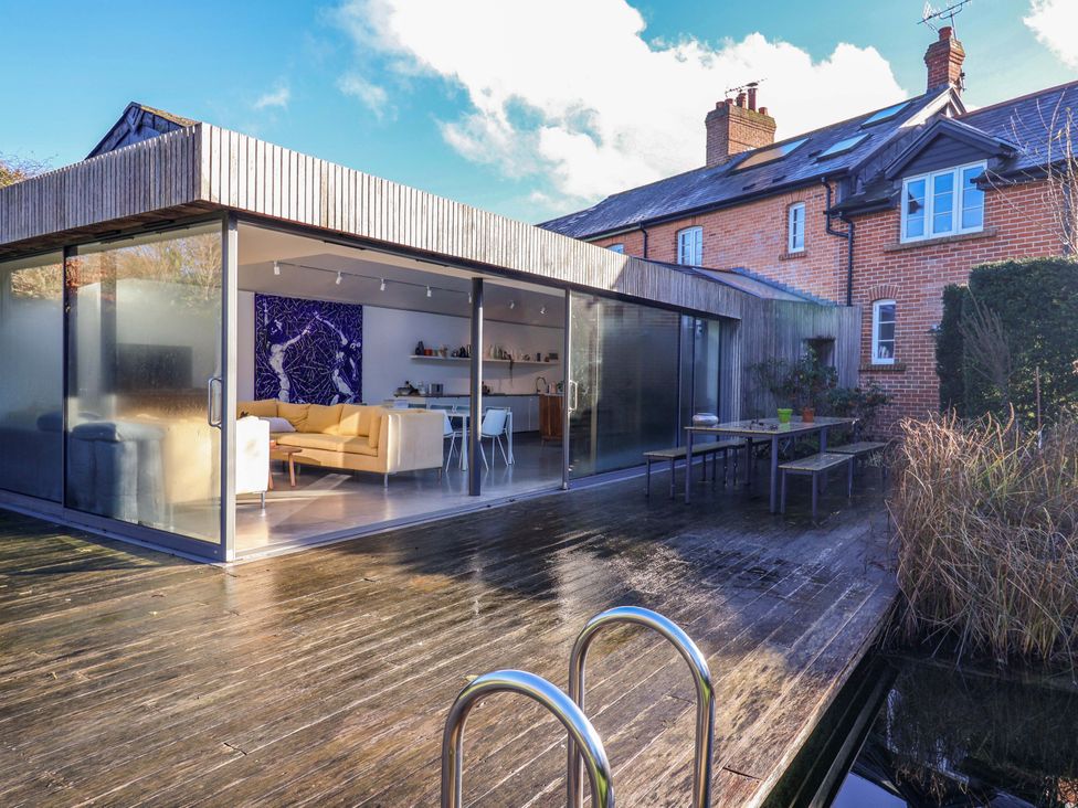 An outdoor space with a glass door and seating area at 2 Bredy Cottages in Burton Bradstock