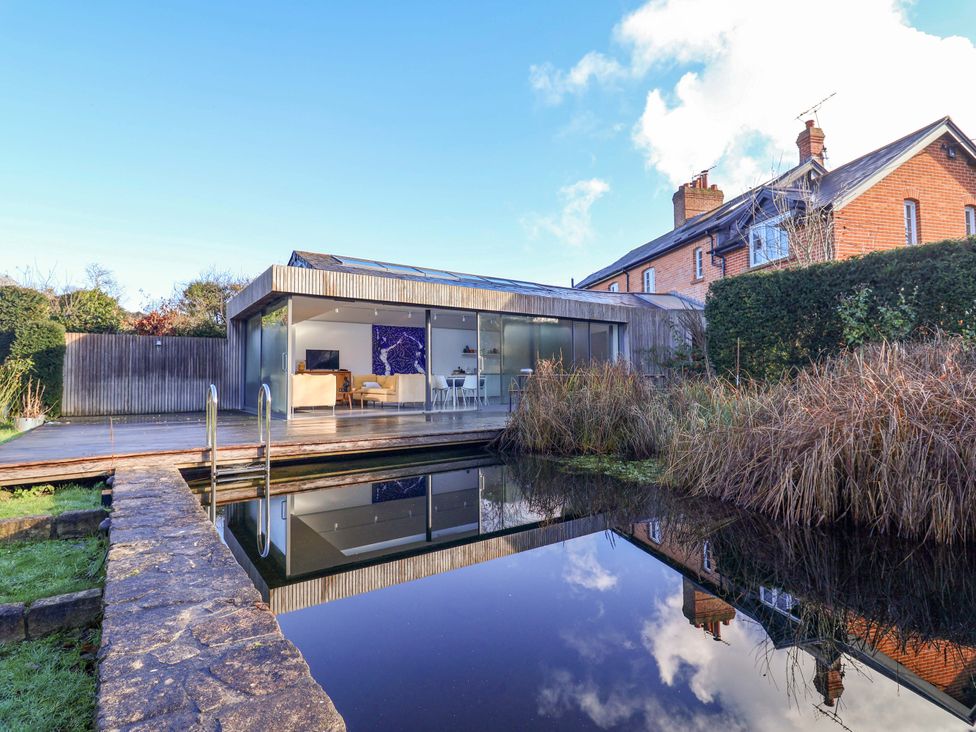 A modern house with a pond and decking at 2 Bredy Cottages Burton Bradstock