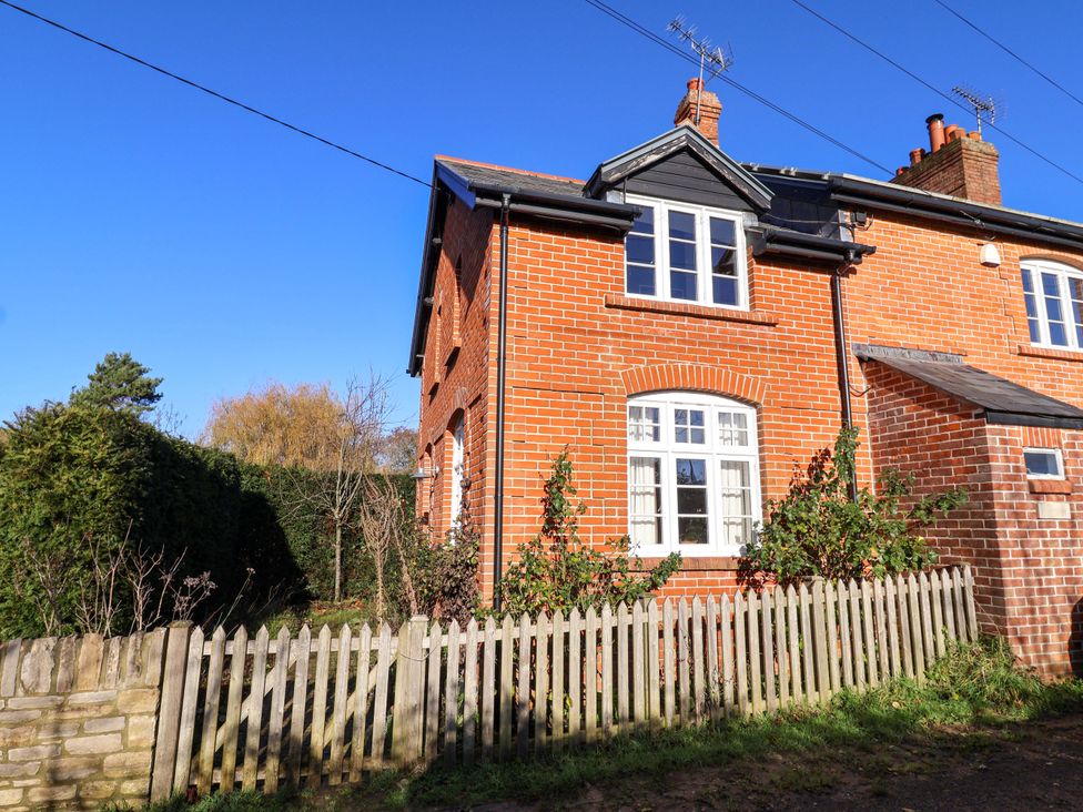 A brick house with a fence and garden at 2 Bredy Cottages Burton Bradstock