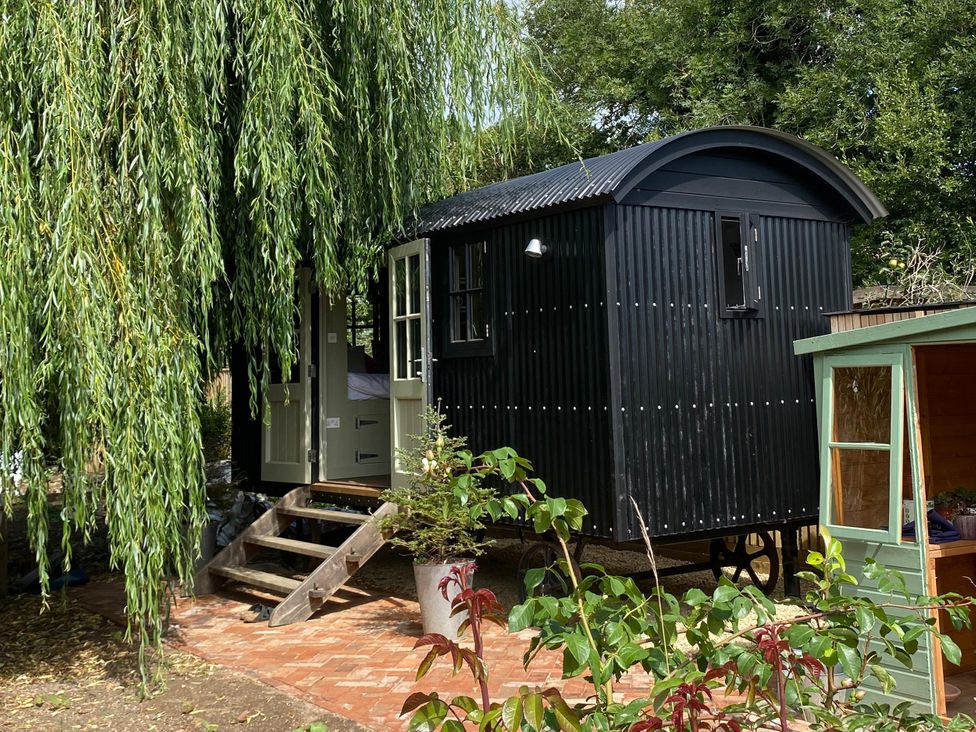 A black shepherd's hut with steps in an outdoor area at 2 Bredy Cottages in Burton Bradstock