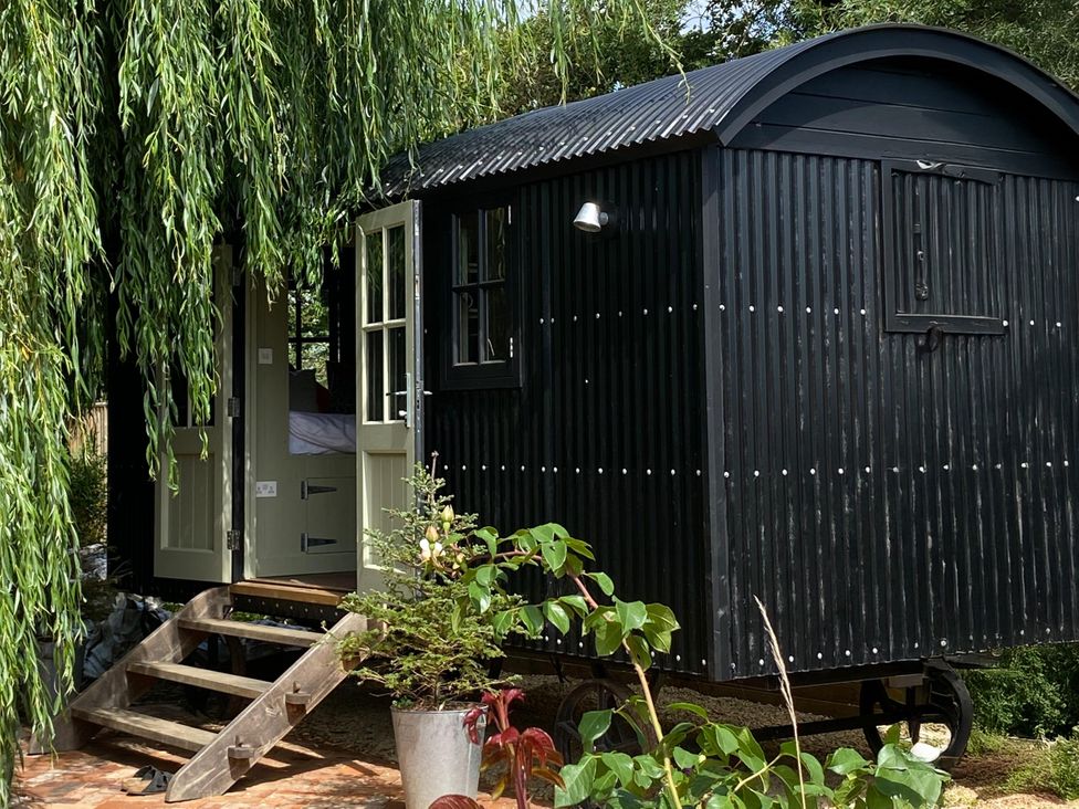 A shepherd's hut with steps and plants at 2 Bredy Cottages Burton Bradstock