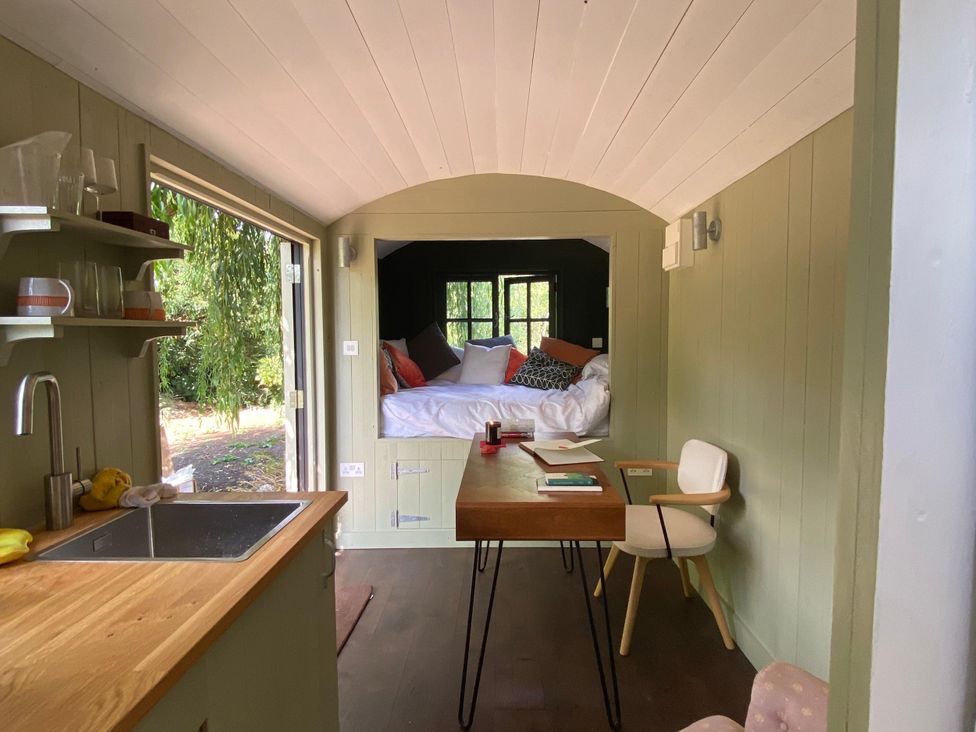 A living room with a bed, table, and chair at 2 Bredy Cottages in Burton Bradstock