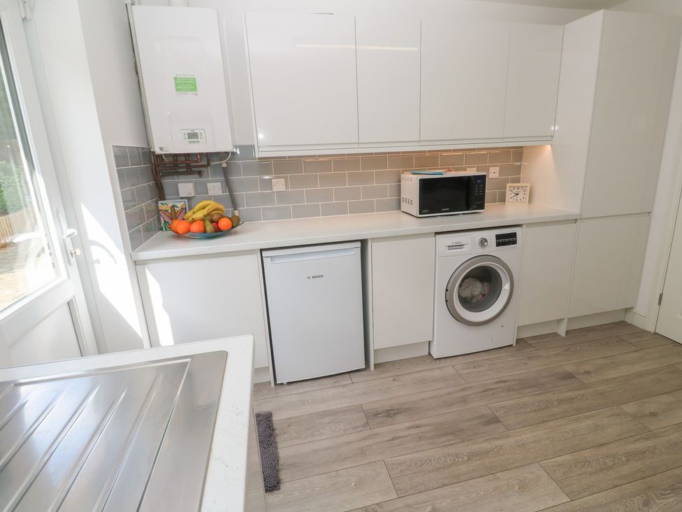 A kitchen with a washing machine and microwave at Jaluna in Carbis Bay