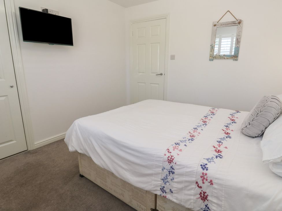 A bedroom with a bed, television, and mirror at Jaluna in Carbis Bay