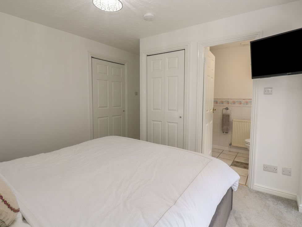 A bedroom with a bed and doors leading to a bathroom at Jaluna in Carbis Bay