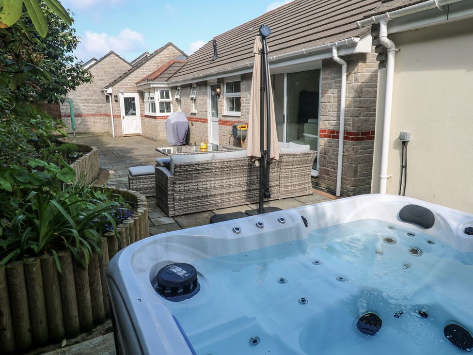An outdoor area with a hot tub and seating at Jaluna in Carbis Bay