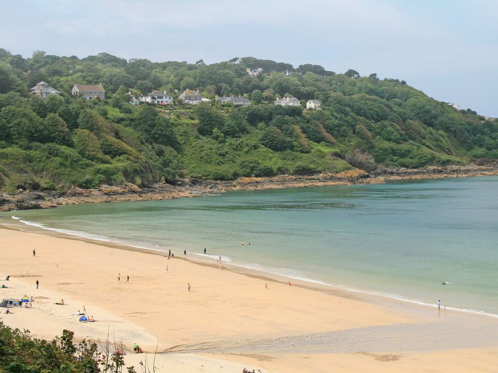 A beach with people and houses on the hill at Jaluna in Carbis Bay