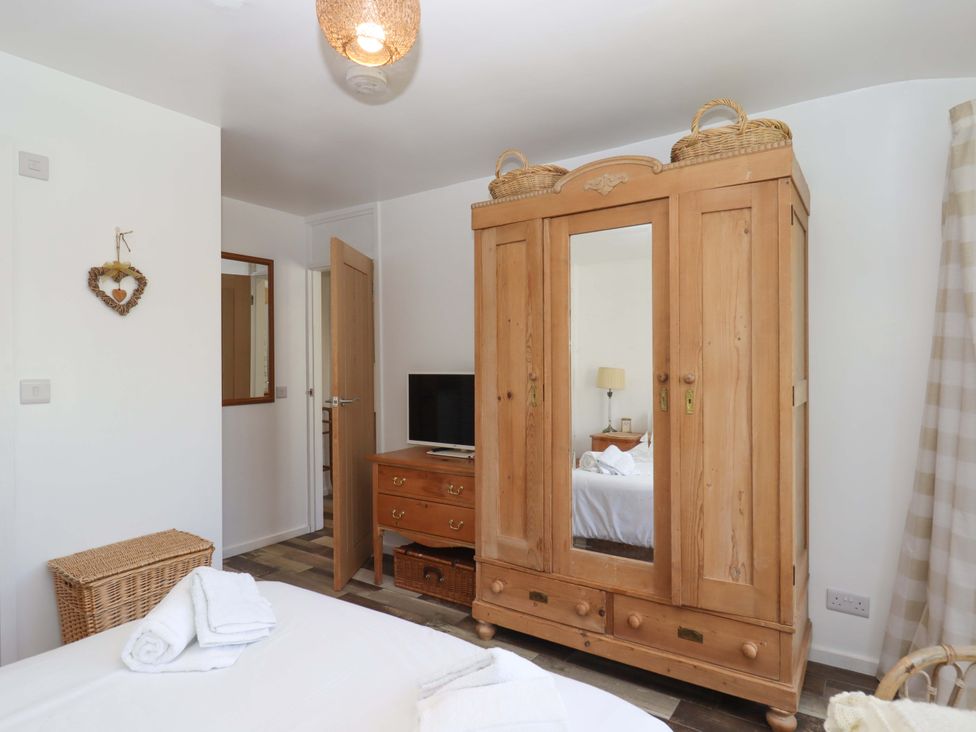 A bedroom with a wardrobe and television at Rowan in Brixham