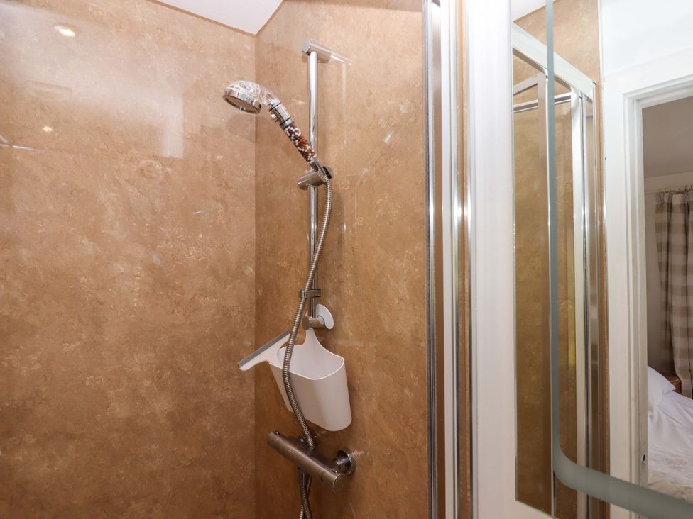 A shower with a wall and controls at Rowan in Brixham