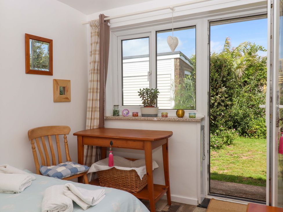 A bedroom with a table and chair near a window and door at Rowan in Brixham