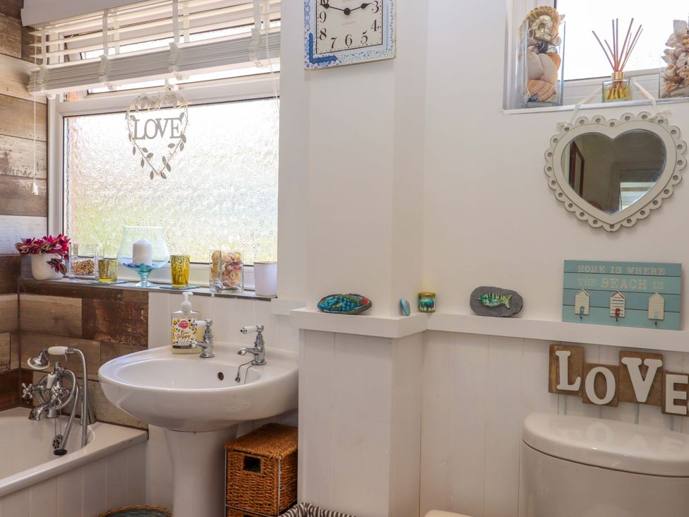 A bathroom with a bathtub and wash basin at Rowan Brixham
