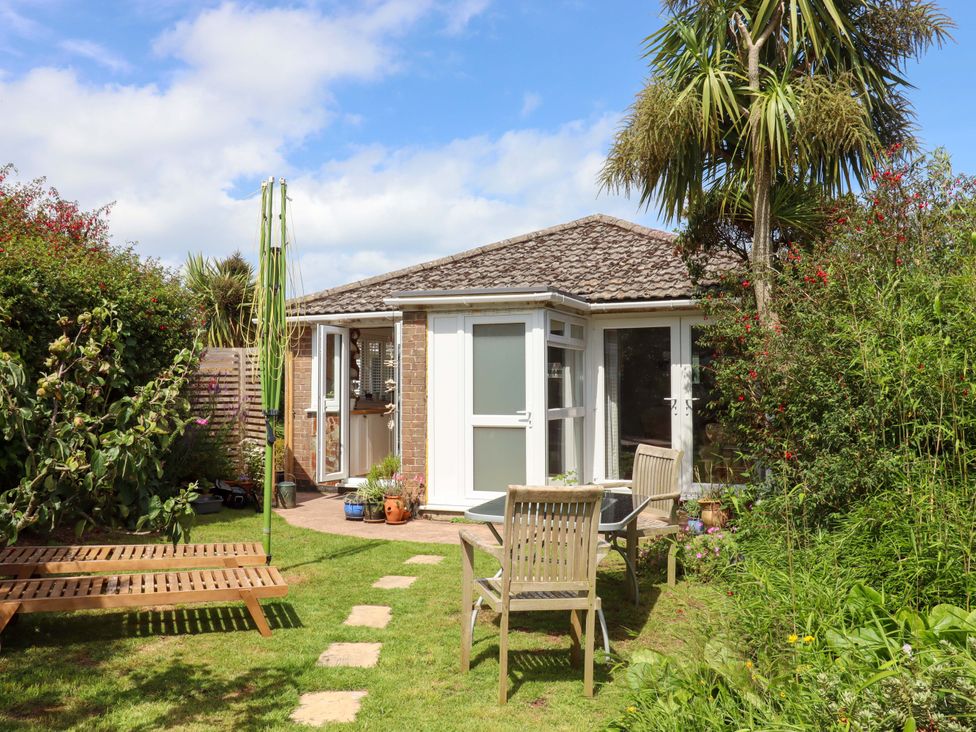 A garden with chairs and a table near a building at Rowan in Brixham