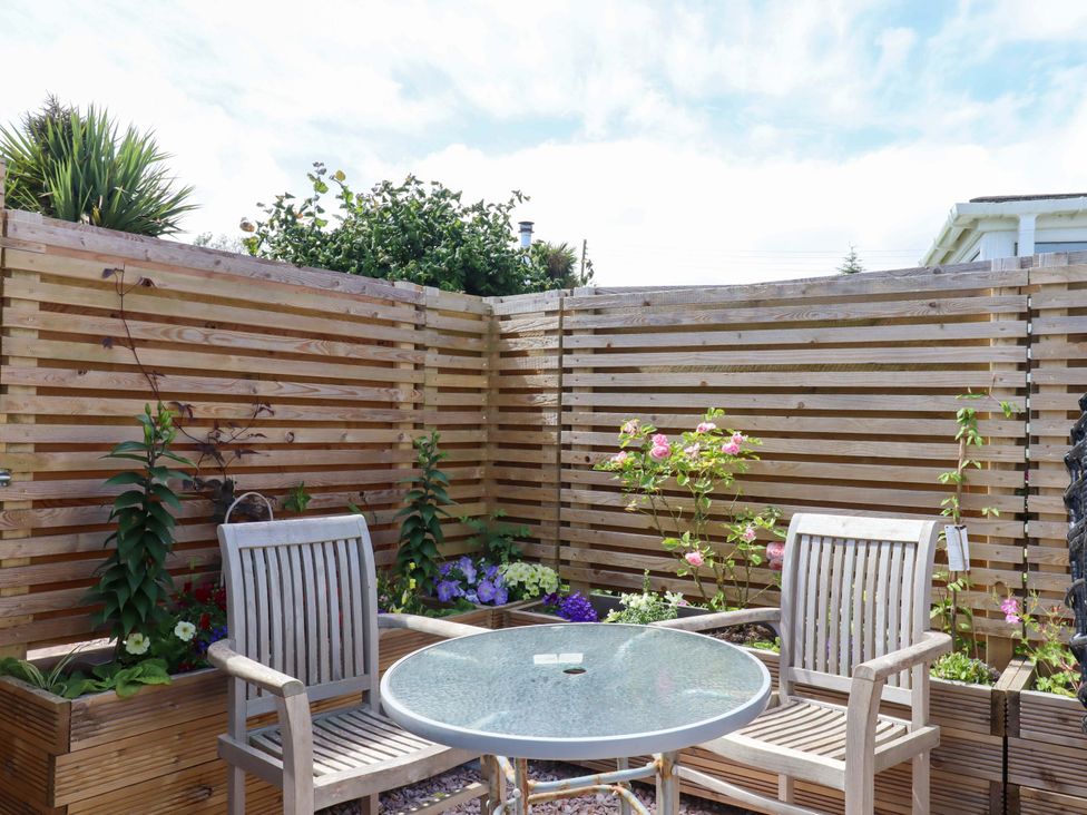 A garden with chairs and a table surrounded by plants at Rowan Brixham