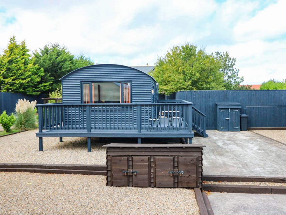 A cabin with a deck and storage box in a garden at Ava Lodge West Mains near Haggerston