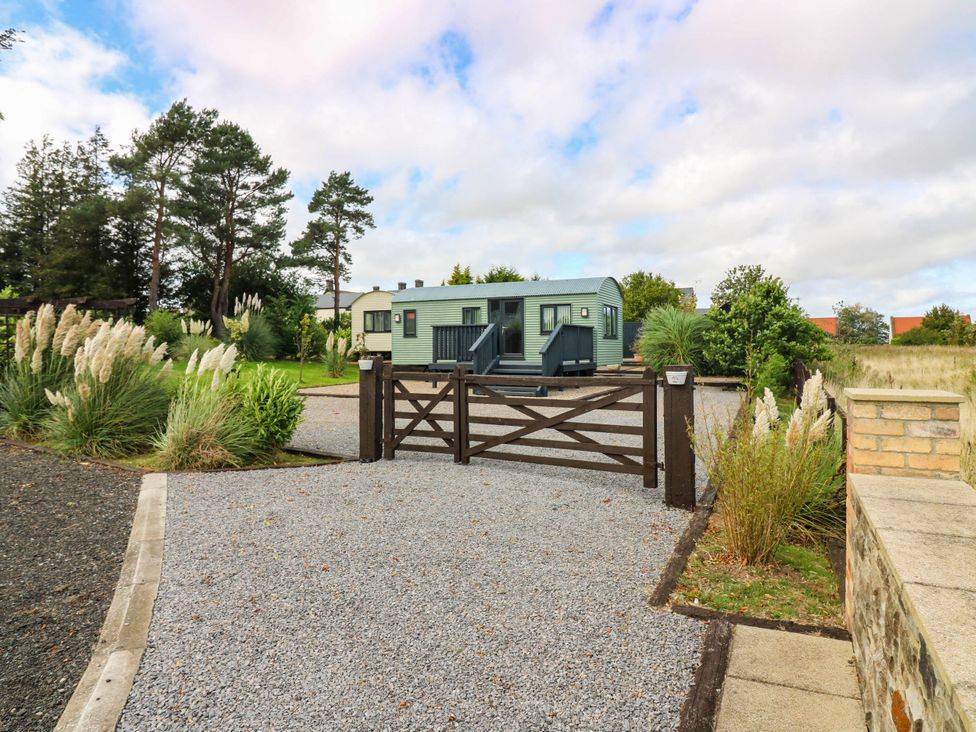 A caravan at the entrance with a gravel driveway at Ava Lodge in West Mains near Haggerston