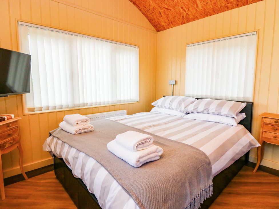A bedroom with a double bed and television at Masons Hut near Haggerston