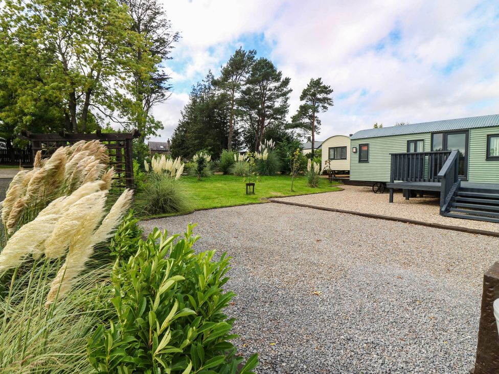 A garden with a caravan and gravel driveway at Masons Hut West Mains near Haggerston
