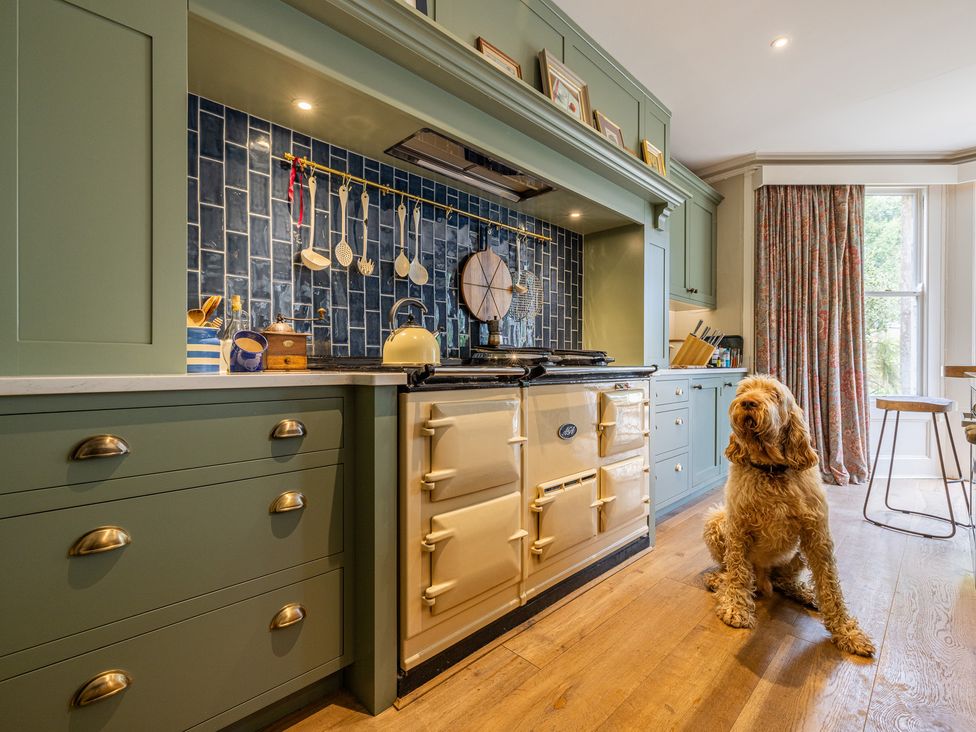 A kitchen with cabinets and a dog sitting on the floor at The Old Vicarage in Merriott