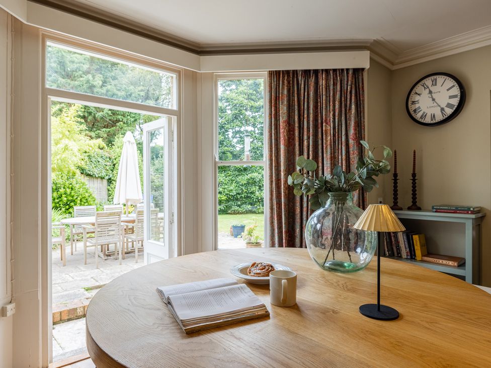 A dining room with a round table and view of the garden at The Old Vicarage in Merriott