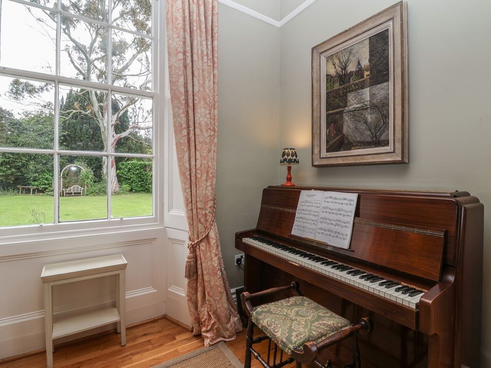 A music room with a piano and sheet music at The Old Vicarage in Merriott