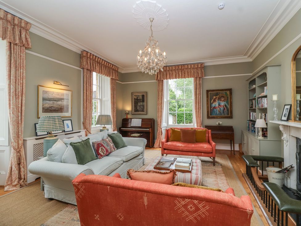 A living room with a chandelier, sofas, and a piano at The Old Vicarage in Merriott
